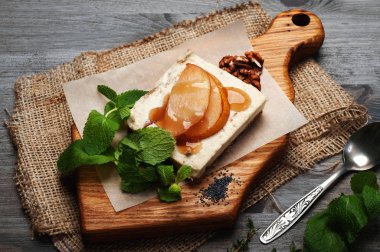 Çiğ gıda tatlı. Hindistan cevizi sütü, kaju fıstığı ve şekersiz şurubu bir yastık tohumlar, kurutulmuş meyve ve fındık yapıştırın. Armut dilimleri ve şurubu üsttedir. Hiçbir pişirme.