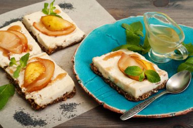 Çiğ gıda tatlı. Hindistan cevizi sütü, kaju fıstığı ve şekersiz şurubu bir yastık tohumlar, kurutulmuş meyve ve fındık yapıştırın. Armut dilimleri ve şurubu üsttedir. Pişirme yok. Yan görünüm