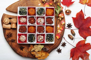 Kurutulmuş meyveler, fındık, tohum, baharat ve baharat meşe panosunda beyaz kutu içinde ilave vegan (çiğ gıda) tatlılar. Beyaz arka plan. Yukarıdan görüntülemek.