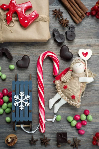 新年とクリスマスのコンセプトです クリスマス ツリー グッズ天使 キャラメル チョコレート 赤い果実 木製の背景が灰色の他の項目 — ストック写真