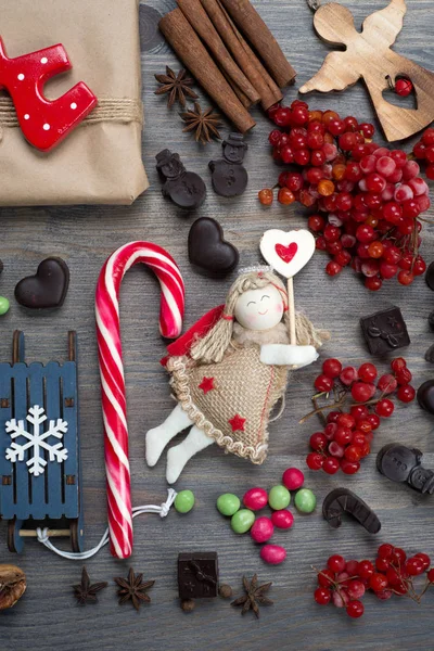 新年和圣诞节的概念 圣诞树玩具天使 巧克力 红色浆果和其他项目在灰色木背景 — 图库照片