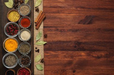 Spices and seasonings on the brown wooden background. Place for text. clipart