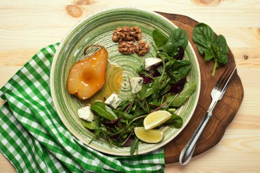 Armut, demlenmiş bal, salata karışımı ile genç ıspanak, roka, pancar yaprakları, mavi peynir, ceviz ahşap tahta üzerinde yeşil bir tabakta. Lezzetli, gurme salata