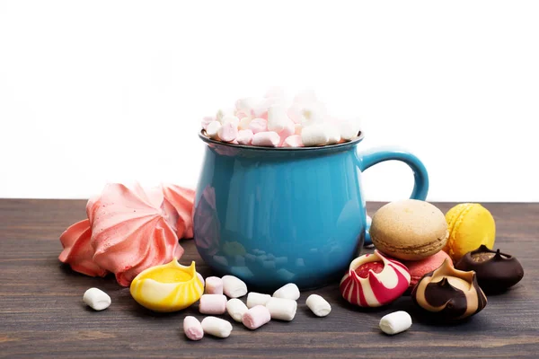 Blue cup with cocoa and marshmallows, alongside refined sweets, — Stock Photo, Image