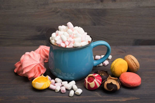 Blue cup with cocoa and marshmallows, near refined sweets, macar — Stock Photo, Image