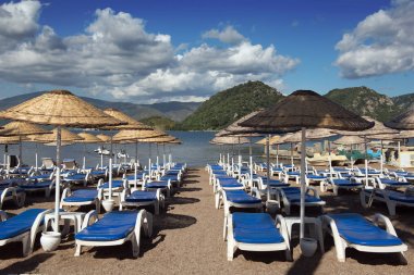 Beach. Şemsiyeler ve şezlonglar, parlak mavi gökyüzü ve deniz. Seyahat ve tatil konsepti