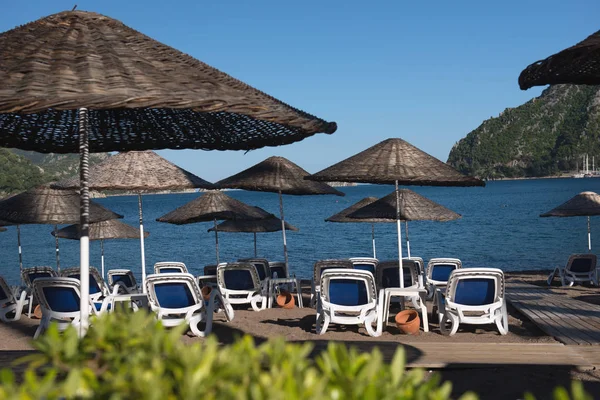 Marmaris, Türkiye'de plaj. Hasır ve mavi yatak, parlak mavi gökyüzü ve deniz şemsiyeleri. Seyahat ve tatil konsepti