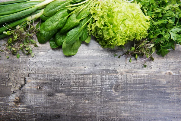 Fondo de primavera. Las espinacas, el perejil, la lechuga, el microverde, la cebolla verde sobre la tabla gris. Lugar para el texto (espacio vacío ) —  Fotos de Stock