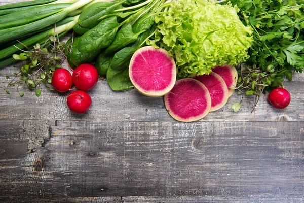 Fundo de primavera. Espinafre, salsa, alface, microverde, cebolas verdes, rabanete em uma tábua cinza. Lugar para texto (espaço vazio ) — Fotografia de Stock