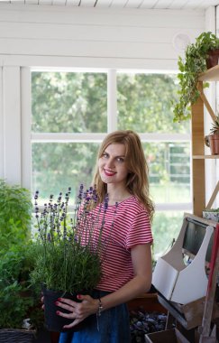 Güzel genç kadın verandada kalmak ve bir pot tutarak