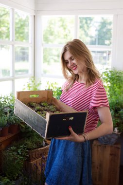 Genç güzel kadın bir bitki deposunda ayakta ve bir bo tutan