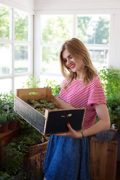 Genç güzel kadın bir bitki deposunda ayakta ve bir bo tutan