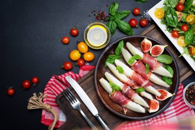 Koyu bir arka plan üzerinde jamon ile kavun meze. Kiraz tom yakınında