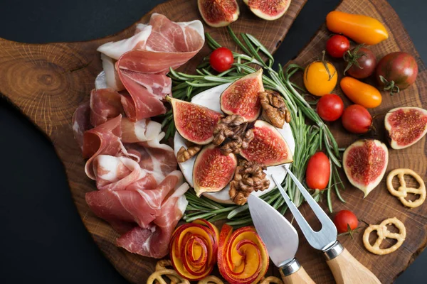 Camembert mit Rosmarin und Feigen auf einem braunen Holzbrett. — Stockfoto