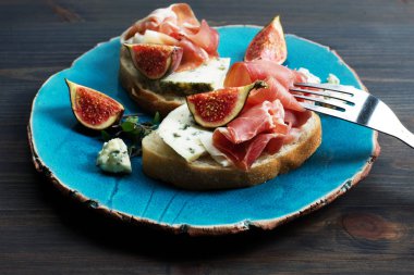 Mavi bir tabakta jambon, mavi peynir ve incir ile Sandviç