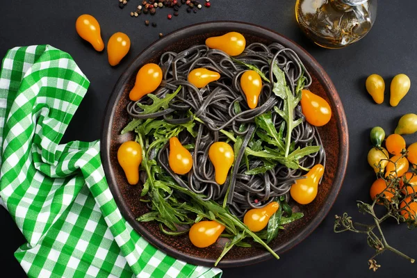 Massa preta com tomates cereja amarelos suculentos brilhantes na forma — Fotografia de Stock