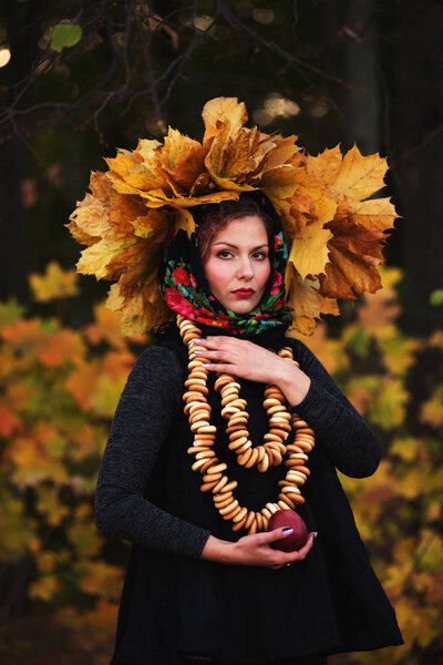 Beautiful young girl dressed in modern Slavic ethno style, against the backdrop of an autumn forest. Shallow depth of field, selective focus, author retouch