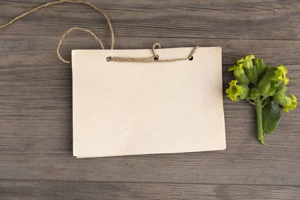 Tobacco flower with handmade craft notebook on old grunge wooden background. Top view. Minimalistic mockup.