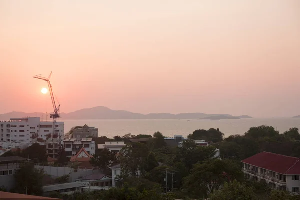 Building on the sea cost. Construction equipment at pink sunset. Real estate on the beach.