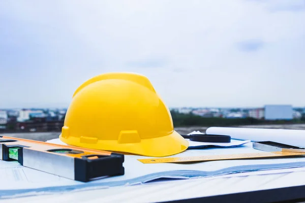 Engineer constrction safety helmet and other tools on top of building blueprint outside at construction site, good for construction or building theme background