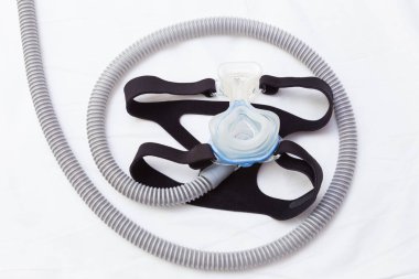 CPAP maske ve şapkalar beyaz yatakta hortumla