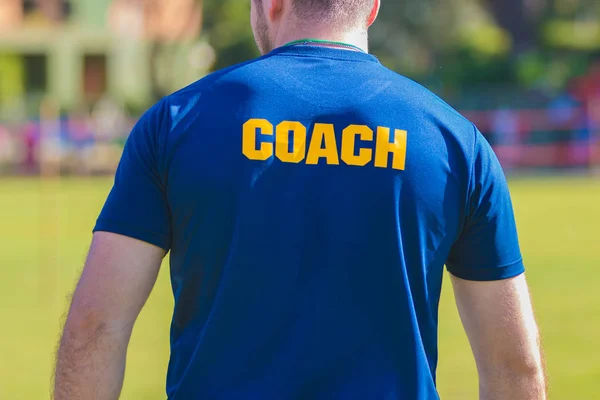 Sporttrainer Blauem Hemd Mit Gelbem Trainer Schriftzug Auf Dem Rücken — Stockfoto