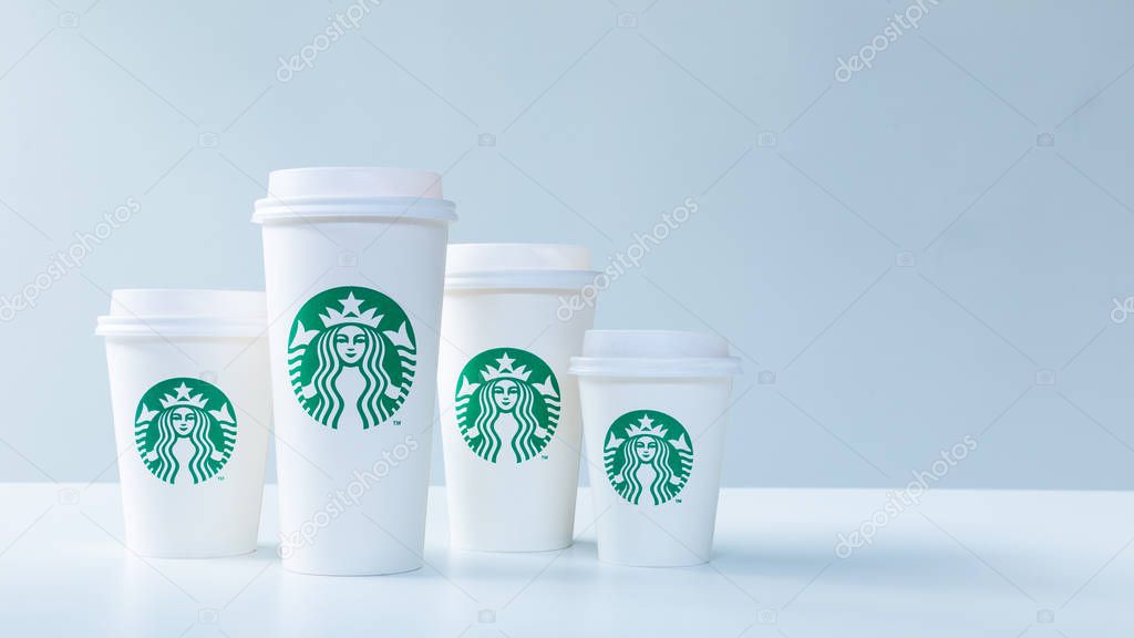 CHIANG MAI, THAILAND - 31 December 2018 - Starbucks white take home coffee cups in various sizes line up on white table against white background in Chiang Mai, Thailand on December 31, 2018