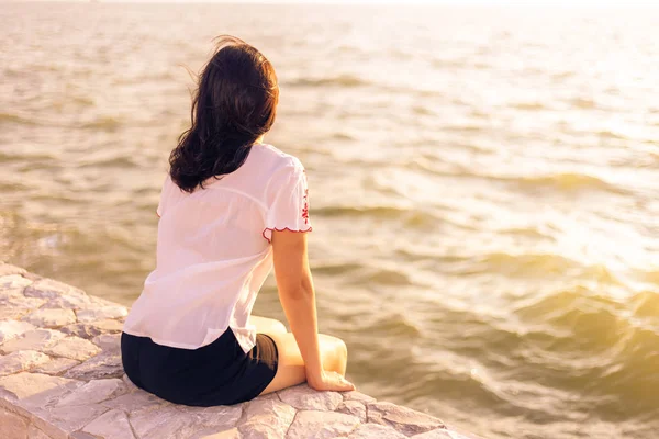 Mujer Joven Sentada Pared Piedra Disfrutando Viendo Puesta Sol Playa — Foto de Stock