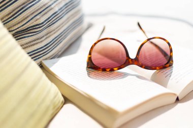 Üstünde tepe-in açık bir kitap yanında döşeme kadın güneş gözlüğü yumuşak yastık, rahat için güneşli açık, iyi ve yaşam tarzı kavramı relax
