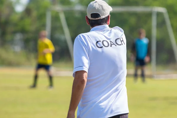 Bir açık futbol sahası, oyun yön vererek onun futbol takımı konuşuyor beyaz koç gömlek giymiş erkek teknik direktör arkası