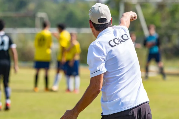 Ekibi bir oyun sırasında iyi spor için koçluk ya da kavram koçluk bir açık spor alanı beyaz koç gömlek giymiş teknik direktör arkası
