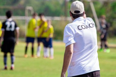 Ekibi bir oyun sırasında iyi spor için koçluk ya da kavram koçluk bir açık spor alanı beyaz koç gömlek giymiş teknik direktör arkası