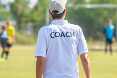 Ekibi bir oyun sırasında iyi spor için koçluk ya da kavram koçluk bir açık spor alanı beyaz Koç gömlek giymiş erkek teknik direktör arkası