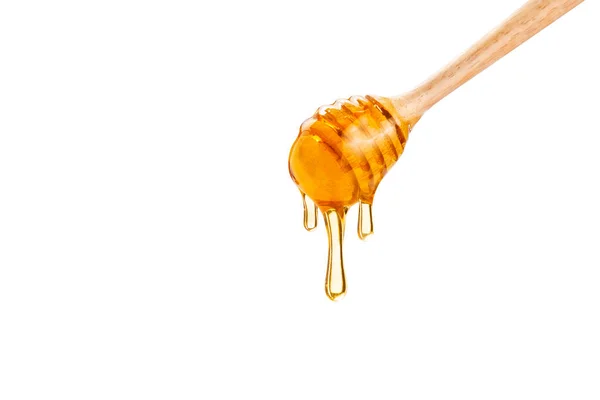 Miel que gotea abajo de la cacerola de madera de la miel, sobre fondo blanco —  Fotos de Stock