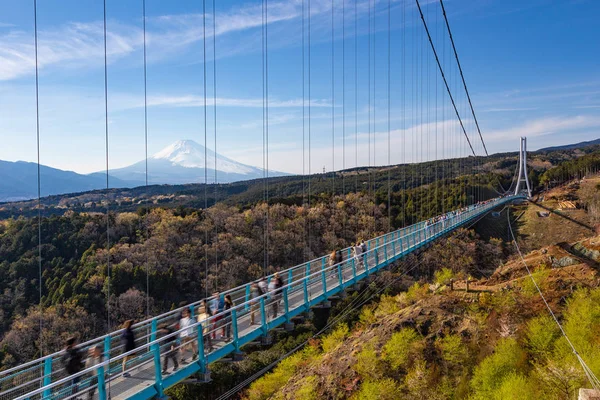 İnsanlar Mishima Skywalk köprüsünde yürürken Fuji Dağı'nda 