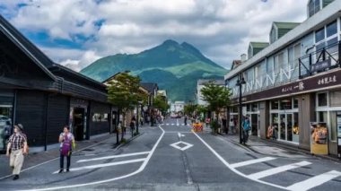 Yufuin, Japonya - 12 Temmuz 2019 - Turistler, Yufuin, Japonya'daki tren istasyonundan ana yol boyunca arka planda dağın manzarasıyla alışveriş ve iş alanına doğru yürüyorlar 12 Temmuz 2019