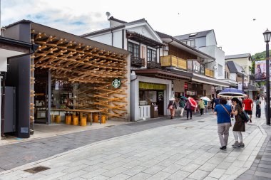 Turistler ve yerel Japon halkı, dükkanlarla çevrili ana yol boyunca yürüyerek Dazaifu, Japonya'daki ünlü Tenmangu Tapınağı'na gidiyor 10 Temmuz 2019