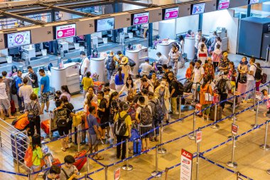 Yolcular Bangkok, Tayland'daki Don Muang Uluslararası Havaalanı check-in kontuarlarında uçuşlarını kontrol etmek için sırada bekliyorlar 