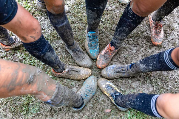 Genç kızlar, futbol maçlarında çamurla kaplı ayakkabılarını göstermek için ayaklarını birleştirirler.