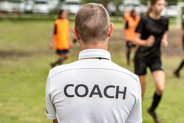 Rückansicht eines männlichen Fußballs, Fußball, Trainer im weißen Trainerhemd beobachtet seine Mannschaft auf einem Fußballplatz im Freien — Stockfoto