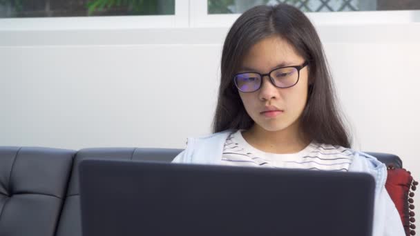 아시아의 소녀는 격리되어 집에서 컴퓨터를 연구하고 있다가 전화를 받는다 — 비디오