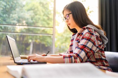 Korona virüsünün yayılması nedeniyle şehir kapatılırken bilgisayarında çalışan ve uzaktan eğitim gören genç Asyalı kız öğrenci.