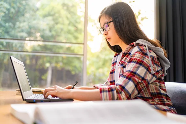 Korona virüsünün yayılması nedeniyle şehir kapatılırken bilgisayarında çalışan ve uzaktan eğitim gören genç Asyalı kız öğrenci.