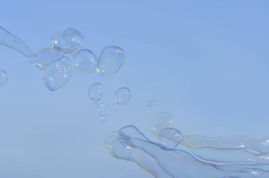 Gökkuşağı parlak yaz mavi gökyüzü arka plan üzerinde büyük kabarcıklar. Sabun köpüğü arka plan, tasarımcılar için öğe