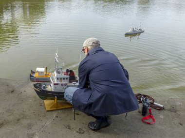 Yaşlı adam iner bir yelken model gemi göl kenarında. Yatay