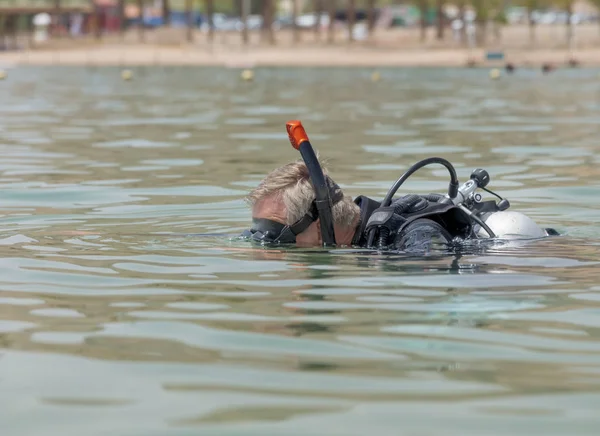 Underwater diver in basic equipment dives into the sea. School of underwater diving. A popular water sport and leisure activity