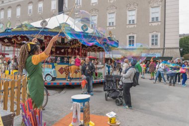 Salzburg, Avusturya - 25 Eylül 2015: Palyaço fuarda sahne alıyor, renkli sabun kabarcıklarını şişiriyor. İnsanlar fuarda eğlenin, Oktoberfest, halk tatili