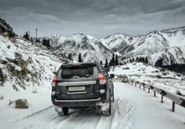 Kışın dağ yolda siyah araba sürmek.