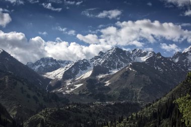 Dağların üst üzerinde beyaz bulutlar ile peyzaj.