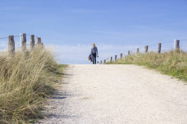girl walking with dog in dunes, Zoutelande, Netherlands clipart
